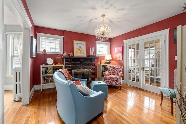 living area featuring a notable chandelier, french doors, a wealth of natural light, and wood finished floors