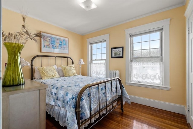 bedroom with radiator, baseboards, wood finished floors, and ornamental molding