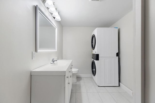 bathroom with stacked washer / dryer, toilet, vanity, and tile patterned flooring