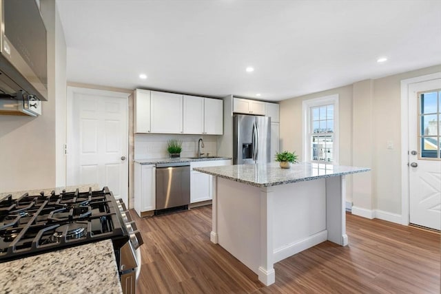 kitchen featuring plenty of natural light, stainless steel appliances, white cabinets, and light stone countertops