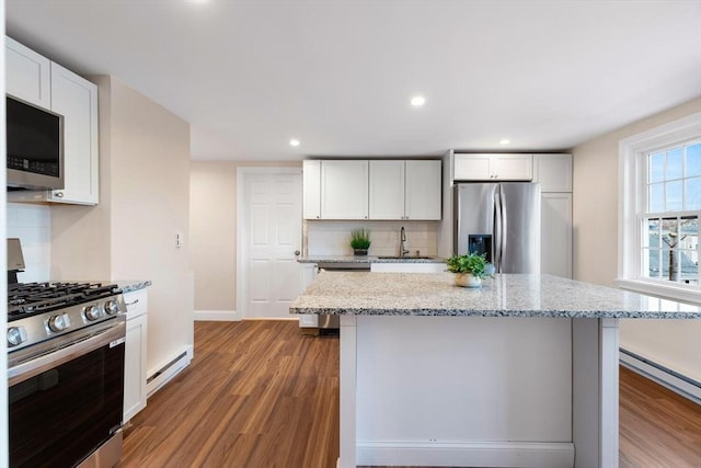 kitchen with appliances with stainless steel finishes, backsplash, white cabinets, and a center island