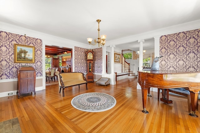 living area featuring ornamental molding, wood-type flooring, a wealth of natural light, and an inviting chandelier