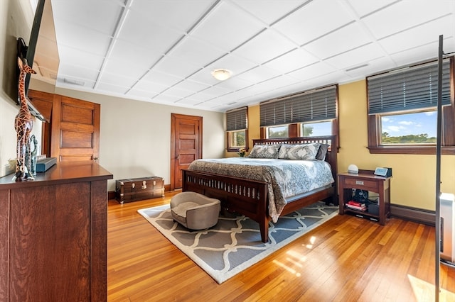 bedroom with light hardwood / wood-style flooring and a baseboard heating unit