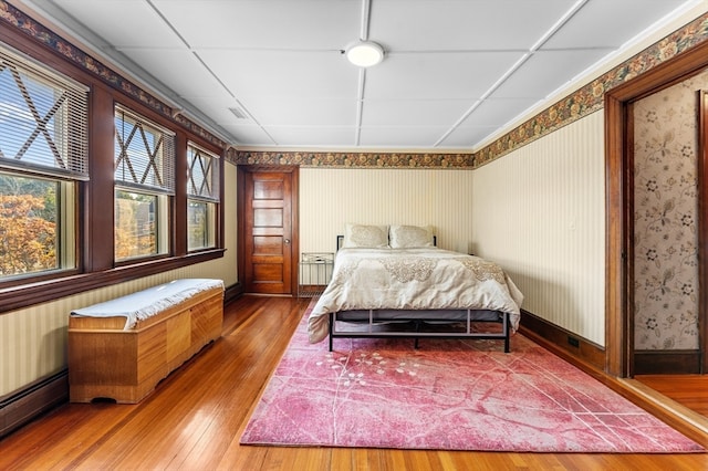 bedroom featuring a baseboard heating unit and hardwood / wood-style floors