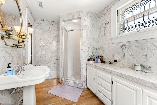 bathroom featuring wood-type flooring, tiled shower, and tile walls