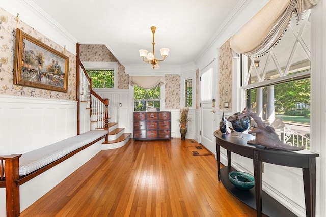 entrance foyer with ornamental molding, wood-type flooring, and a chandelier