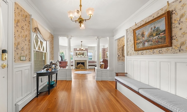 entrance foyer with a notable chandelier, light hardwood / wood-style flooring, decorative columns, and ornamental molding