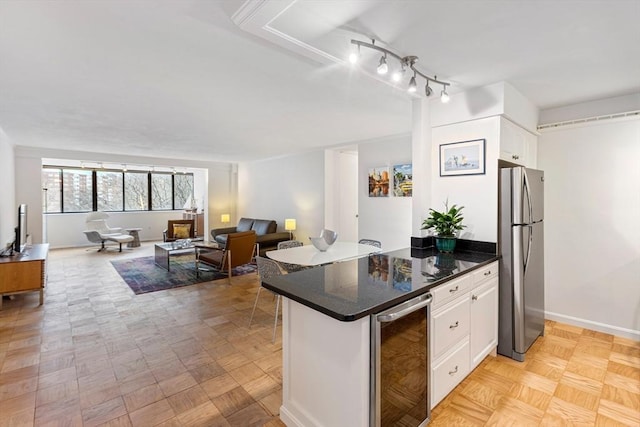 kitchen featuring wine cooler, open floor plan, freestanding refrigerator, a peninsula, and white cabinetry