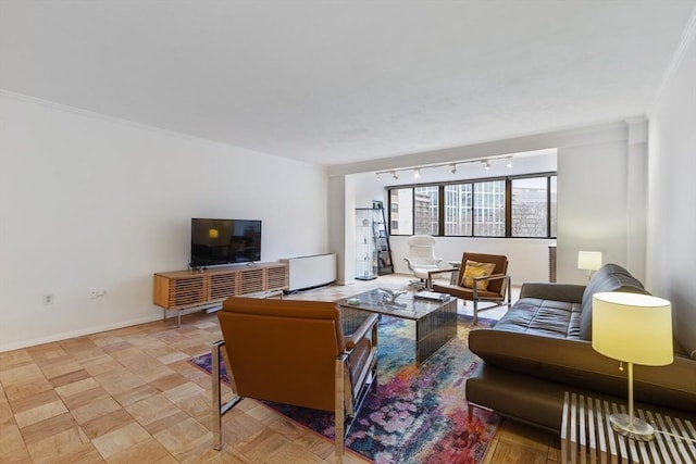 living area featuring rail lighting, baseboards, and crown molding