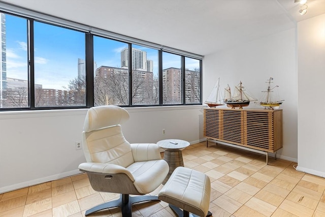 sitting room featuring a view of city, light tile patterned floors, and baseboards