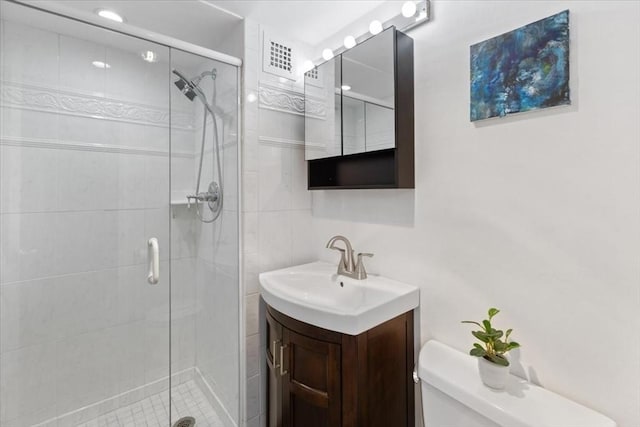 bathroom with toilet, a shower stall, visible vents, and vanity