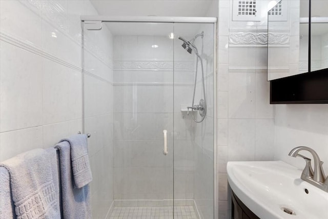 bathroom with a shower stall, tile walls, and vanity