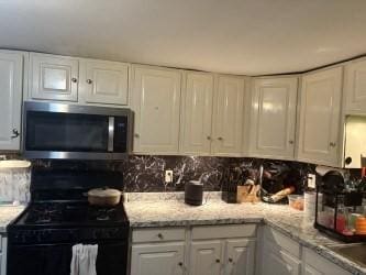 kitchen with stainless steel microwave, white cabinetry, gas stove, and tasteful backsplash
