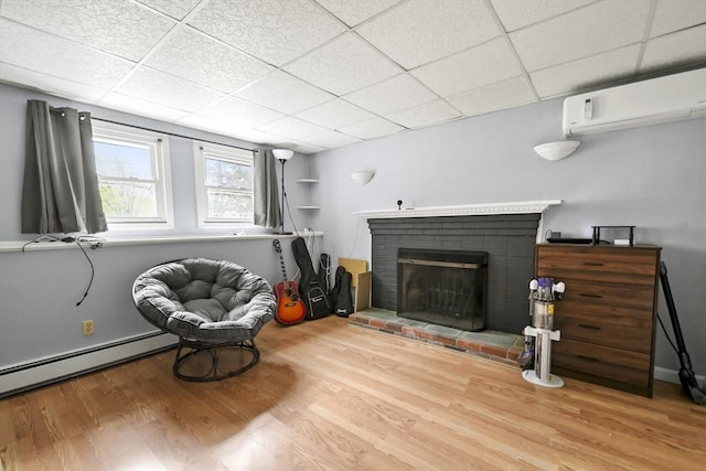 24 Highland Ave, Millbury, MA 01527 - living area featuring wood finished floors, a drop ceiling, baseboard heating, a brick fireplace, and an AC wall unit