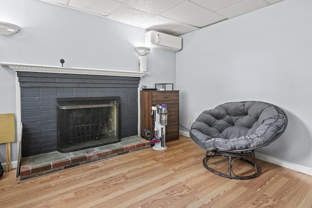 24 Highland Ave, Millbury, MA 01527 - sitting room featuring wood finished floors, a brick fireplace, a wall mounted air conditioner, and baseboards