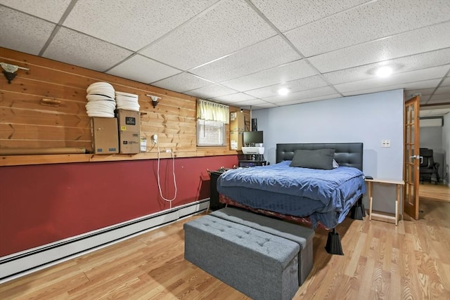 24 Highland Ave, Millbury, MA 01527 - bedroom featuring a baseboard radiator, wood finished floors, a paneled ceiling, electric panel, and wooden walls