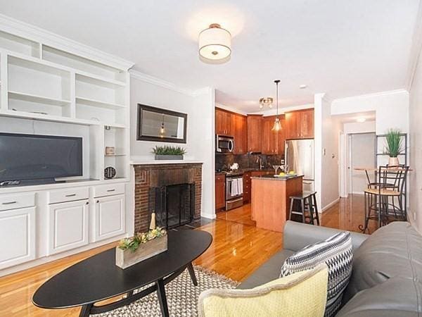 455 Massachusetts Ave Unit 2, Boston, MA 02118 - living room featuring crown molding, light wood-style floors, a fireplace, baseboards, and built in features