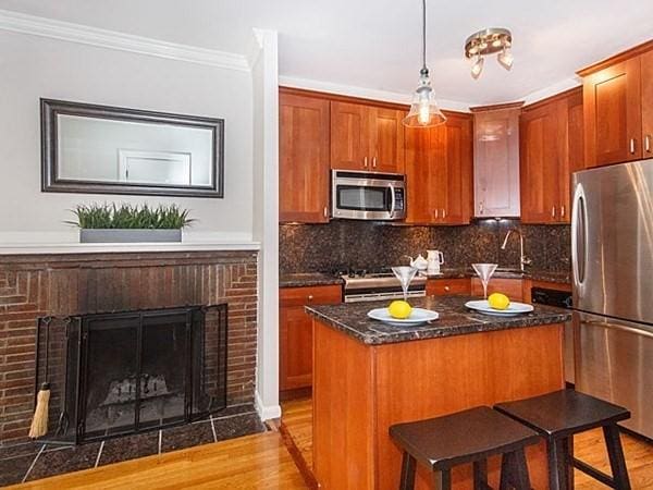 455 Massachusetts Ave Unit 2, Boston, MA 02118 - kitchen featuring appliances with stainless steel finishes, light wood-style flooring, a sink, tasteful backsplash, and ornamental molding