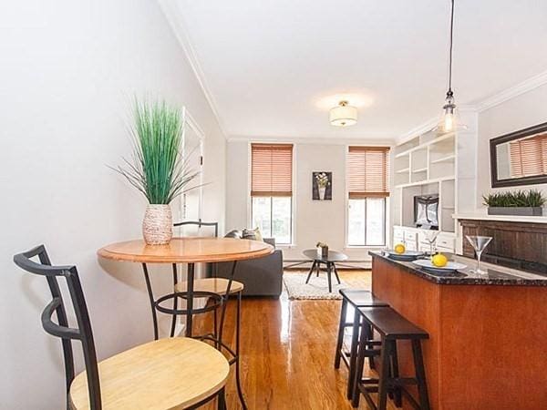 455 Massachusetts Ave Unit 2, Boston, MA 02118 - kitchen with crown molding, wood finished floors, a breakfast bar, decorative light fixtures, and baseboards
