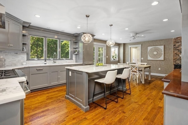 kitchen with gray cabinets, hanging light fixtures, light hardwood / wood-style floors, and a center island