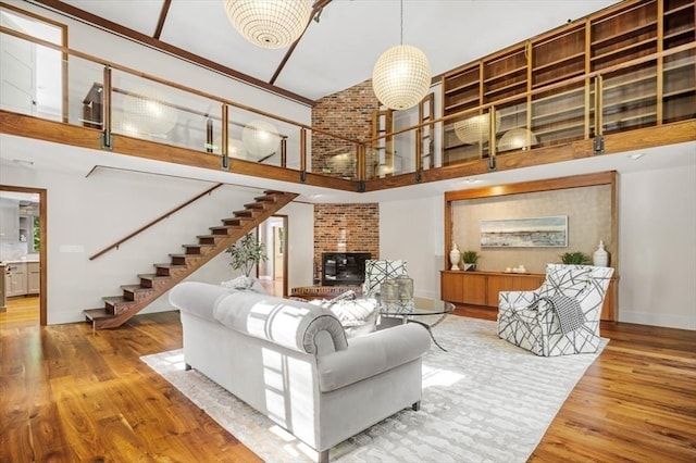 living room with a brick fireplace, a towering ceiling, and light hardwood / wood-style floors