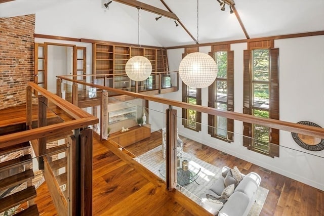 hallway featuring hardwood / wood-style flooring, high vaulted ceiling, and a notable chandelier