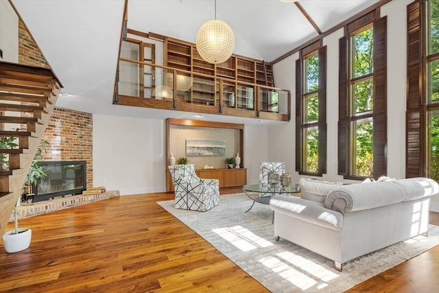 living room featuring high vaulted ceiling, hardwood / wood-style floors, and a fireplace