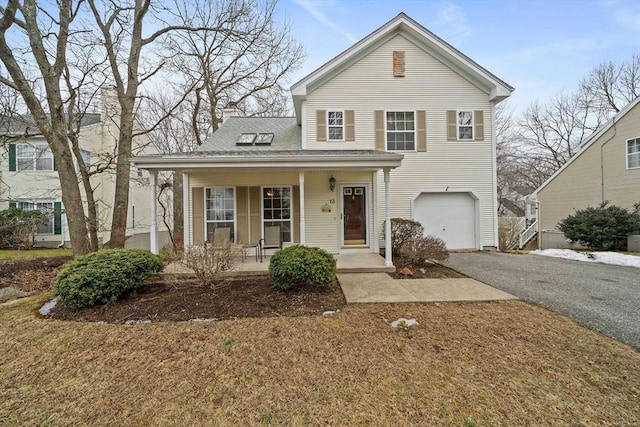 traditional home with a shingled roof, a chimney, aphalt driveway, an attached garage, and a porch