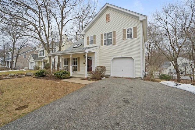 view of front facade with covered porch, driveway, a chimney, and a garage