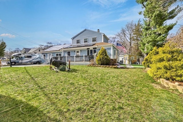 55 Friendship St, Billerica, MA 01821 - back of property featuring a gate, solar panels, a chimney, a wooden deck, and a lawn