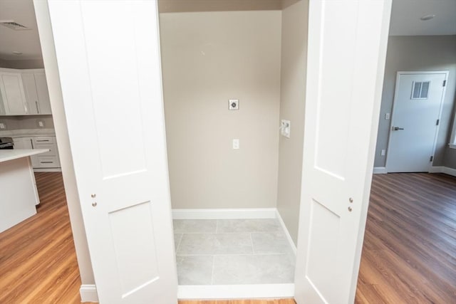 interior space with laundry area, baseboards, visible vents, hookup for an electric dryer, and light wood-style floors