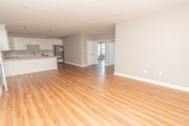 unfurnished living room featuring light wood-type flooring and baseboards