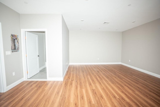 empty room featuring light wood-type flooring, visible vents, and baseboards