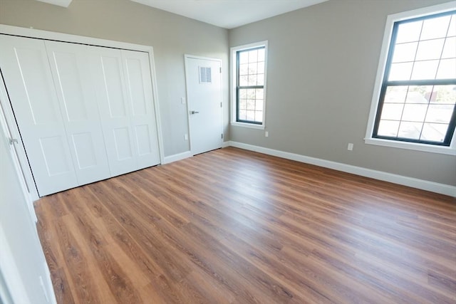 unfurnished bedroom featuring a closet, baseboards, and wood finished floors