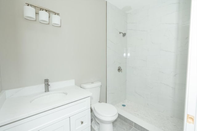 full bathroom featuring vanity, a tile shower, and toilet