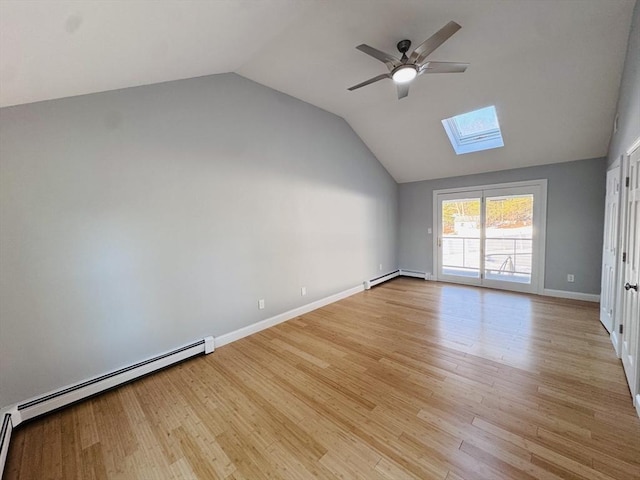 interior space featuring a ceiling fan, a baseboard radiator, vaulted ceiling with skylight, and light wood-style flooring