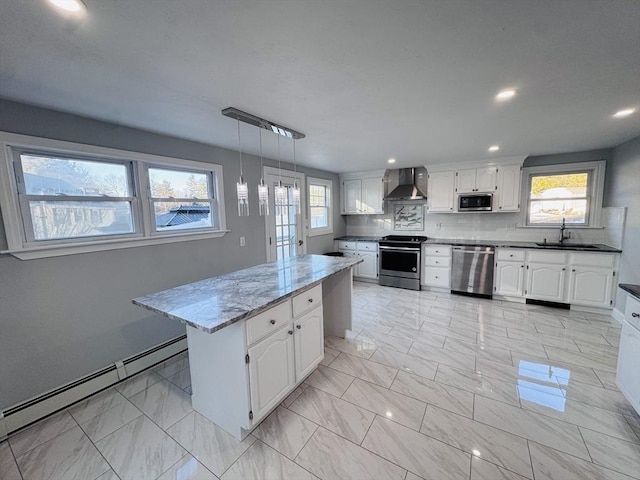 kitchen with marble finish floor, appliances with stainless steel finishes, a baseboard heating unit, a sink, and wall chimney exhaust hood