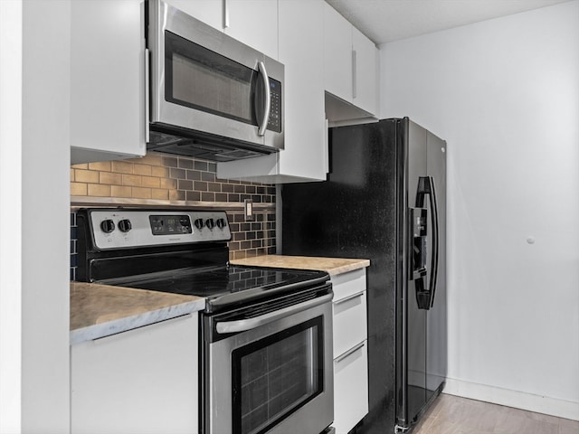 kitchen with appliances with stainless steel finishes, decorative backsplash, light hardwood / wood-style floors, and white cabinetry