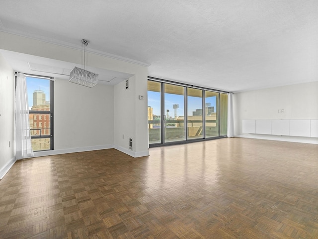 unfurnished room with ornamental molding, dark parquet floors, a textured ceiling, and floor to ceiling windows