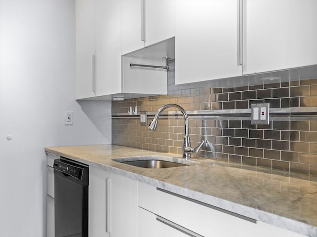 kitchen with black dishwasher, white cabinetry, and sink