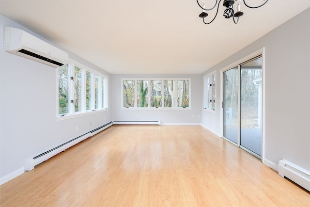 interior space with an inviting chandelier, an AC wall unit, light hardwood / wood-style flooring, and a baseboard heating unit