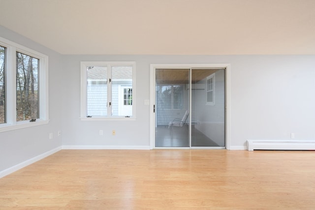 empty room featuring baseboard heating and light hardwood / wood-style flooring