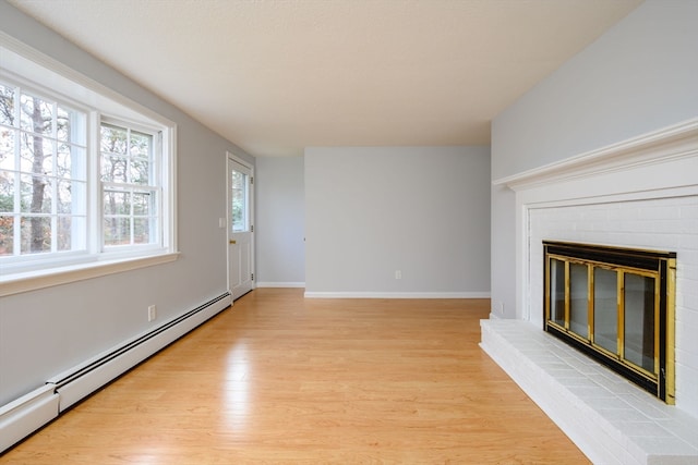 unfurnished living room with a fireplace, light hardwood / wood-style flooring, and baseboard heating