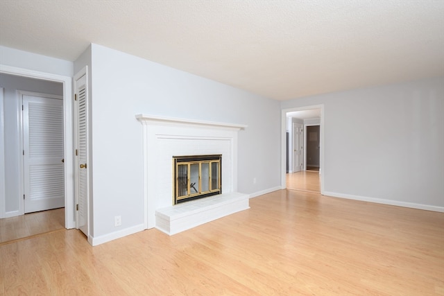 unfurnished living room featuring a textured ceiling, a fireplace, and light hardwood / wood-style flooring