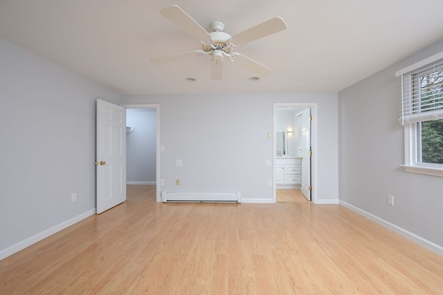 unfurnished bedroom featuring a walk in closet, light wood-type flooring, ensuite bath, ceiling fan, and a baseboard heating unit