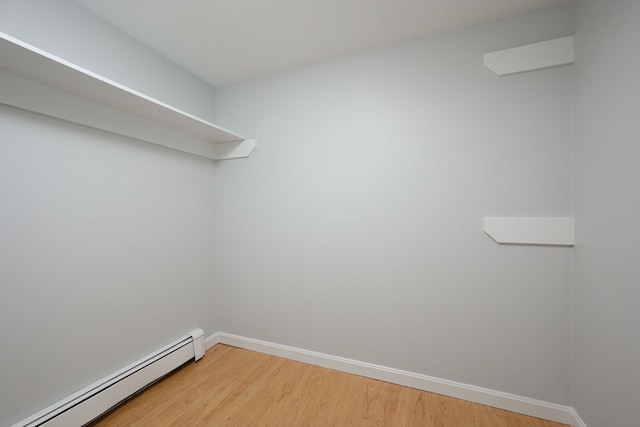 spacious closet featuring hardwood / wood-style flooring and a baseboard heating unit