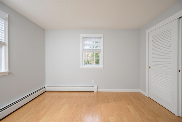 interior space with light wood-type flooring and a baseboard heating unit