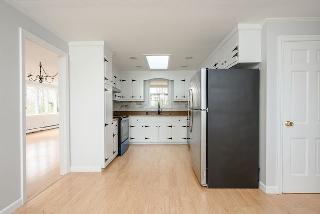 kitchen featuring a wealth of natural light, black electric range oven, white cabinetry, and stainless steel refrigerator