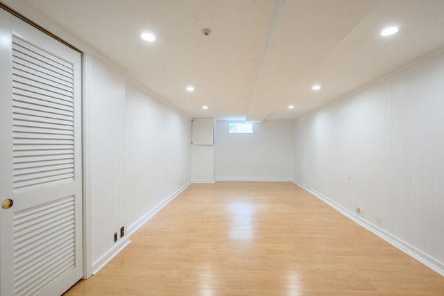 basement featuring crown molding and light hardwood / wood-style flooring