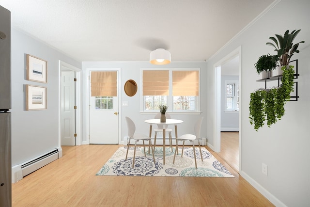 dining space with ornamental molding, a baseboard radiator, and light hardwood / wood-style floors